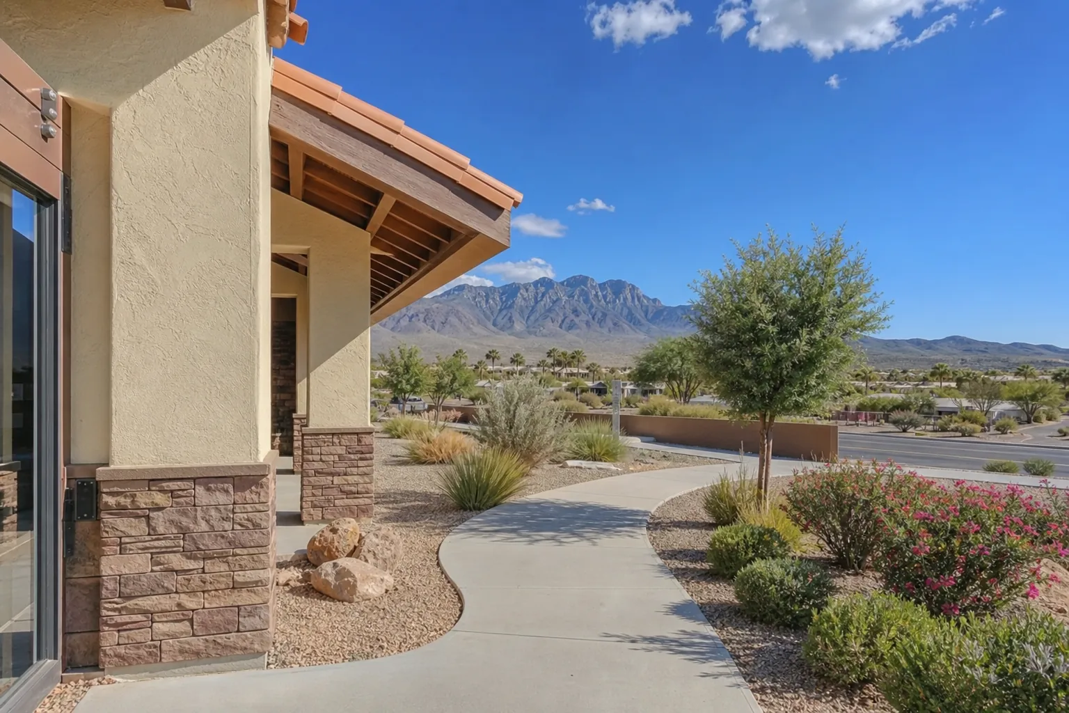 Curved walkway beside a Southwestern-style building with desert landscaping and mountains near Las Cruces