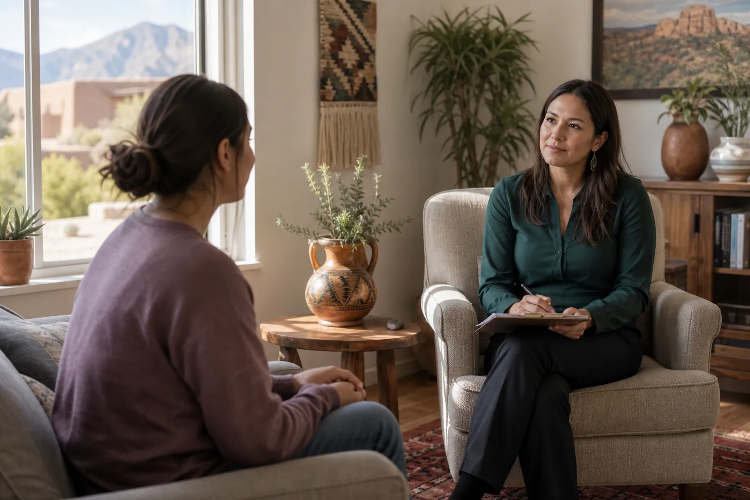 A therapist with a notepad listens to a client during a counseling session in a warmly decorated office.
